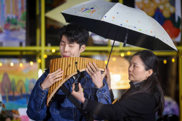 小岱手持排箫立于雨中，以一曲《茶花开了》叩击人心。 